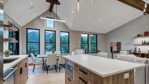 Een moderne keuken met een groot kookeiland, inbouwapparatuur en grote ramen met uitzicht op de omgeving.