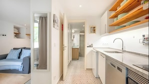 Un espace de vie compact comprenant une kitchenette, un coin repas et une chambre.