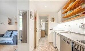 Un espacio habitable compacto con kitchenette, comedor y dormitorio.