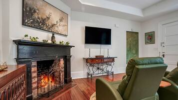 A living room with a fireplace, a television, and a green armchair.