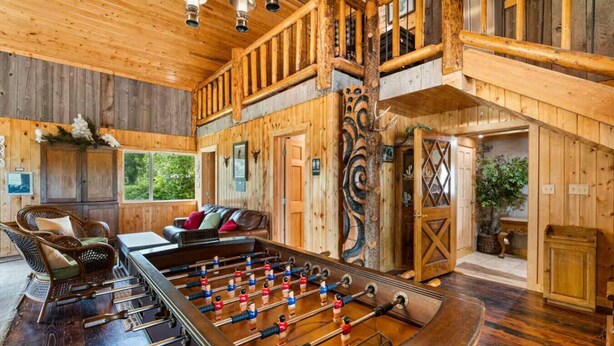 Una habitación amplia con mesa de futbolín, muebles de madera y vista al exterior.