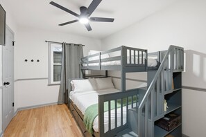 A bunk bed room with a ceiling fan, a window with curtains, and a door. - Home in Overland Park (Overland Park)
