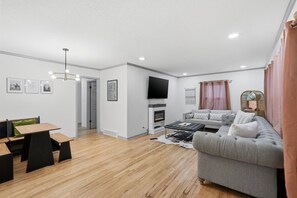 Ein modernes Wohnzimmer mit Kamin, einer Couch, einem Couchtisch und einem an der Wand montierten Fernseher.