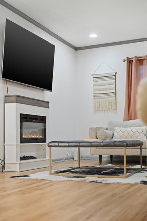 Un saló modern amb televisió plana, llar de foc, sofà i una catifes amb disseny.