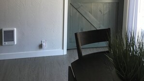 Une pièce avec une porte en bois, une horloge murale, un luminaire au plafond et une prise de courant.
