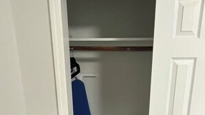 Un placard avec une tringle à vêtements, une porte blanche et un panier à linge.