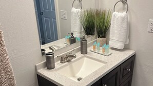 Une salle de bain avec un lavabo blanc, des meubles sombres, un miroir et des toilettes.
