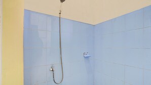 A small, tiled shower area with a handheld showerhead and a wall-mounted faucet. - OYO 95065 Villa Ade (Cisarua)