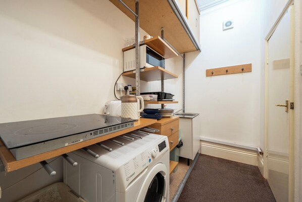 A laundry area with a washing machine, a drying rack, and shelves with various items. - Apartment Sleeps 7 - Contractors,long Stays, Wifi (Birmingham)