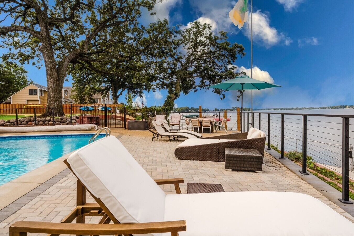 A poolside area with lounge chairs, a table, and a view of the water.