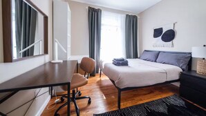 Quarto moderno com cama, escrivaninha, cadeira e um espelho grande.