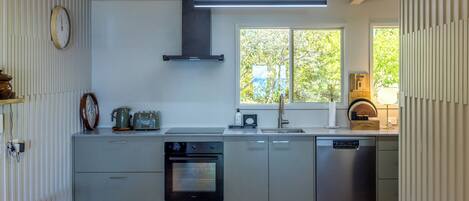 Una cocina moderna con horno empotrado, lavavajillas y ventana que proporciona luz natural.