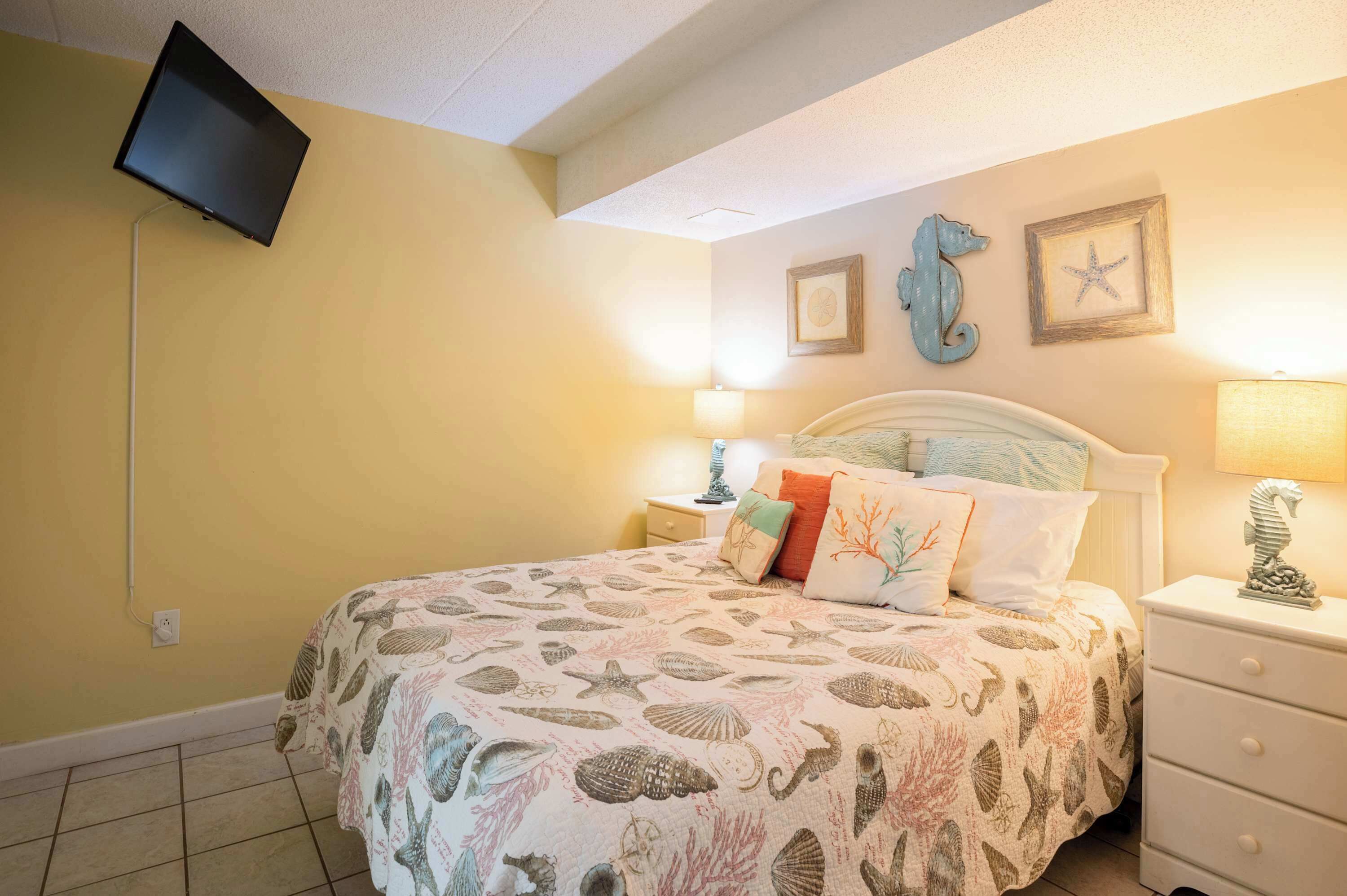 A bedroom with a bed, a nightstand, a lamp, a wall-mounted TV, and decorative wall art.