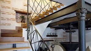 A staircase with wooden steps and a metal railing, leading to a loft area with a large industrial machine and a brick wall. - CASA RURAL TOLANCA. Near Toledo and Puy du Fou (Sonseca)