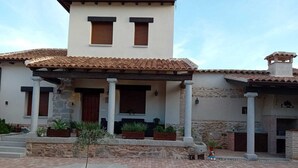 A two-story house with a tiled roof, a covered porch with columns, and a brick patio. - CASA RURAL TOLANCA. Near Toledo and Puy du Fou (Sonseca)