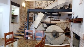 A dining area with a glass table, wooden chairs, a stone fireplace, and a staircase with a metal railing. - CASA RURAL TOLANCA. Near Toledo and Puy du Fou (Sonseca)