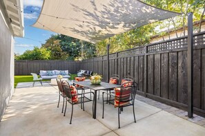 An outdoor patio with a table and chairs, a sofa, and a decorative vase. - Walk to Google Cloud 10 min Google Main Campus (Sunnyvale)