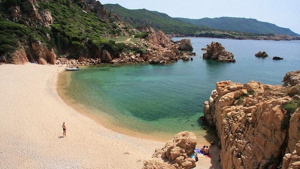 Una spiaggia con acque cristalline turchesi, scogliere rocciose e un litorale sabbioso.