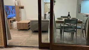 Un soggiorno moderno con un divano, un tavolino, una TV e un'area pranzo con tavolo e sedie.