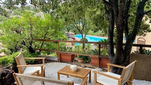 Patio con mobili in vimini, un tavolo e vista su una piscina.