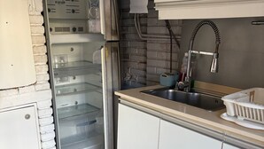 Et lille køkken med et køleskab, en mikrobølgeovn, en vask og en lille bordplade.