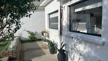 Een schoon, wit gevel van een gebouw met grote ramen, een pad van baksteen en potplanten.