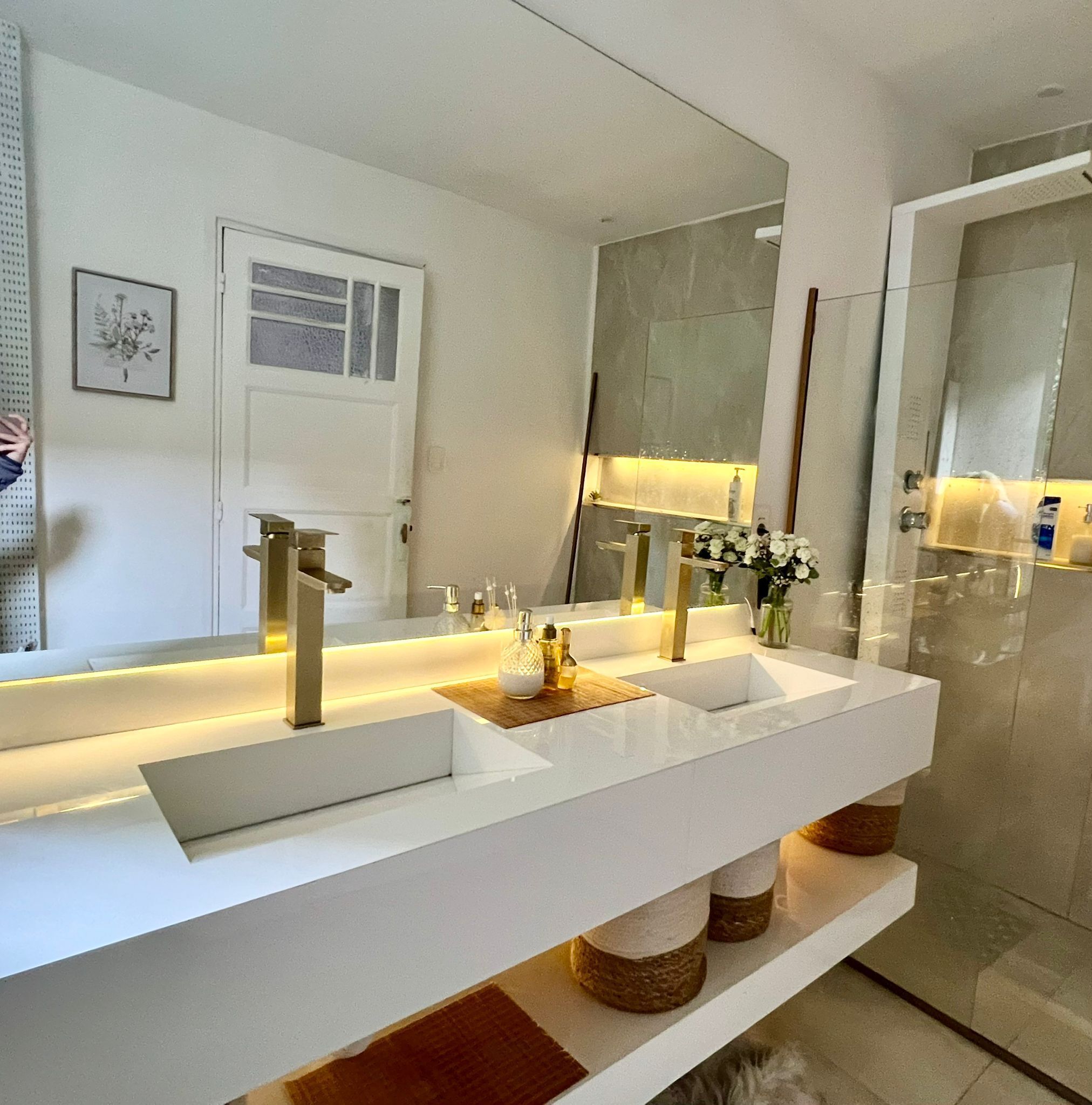 A modern bathroom with two sinks, a large mirror, and a door.