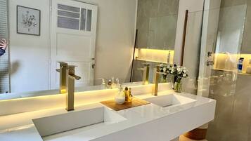 A modern bathroom with two sinks, a large mirror, and a door.