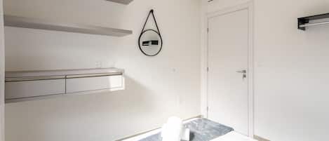 A minimalist bedroom with a bed, a wall-mounted towel rack, a door, and a built-in shelf.