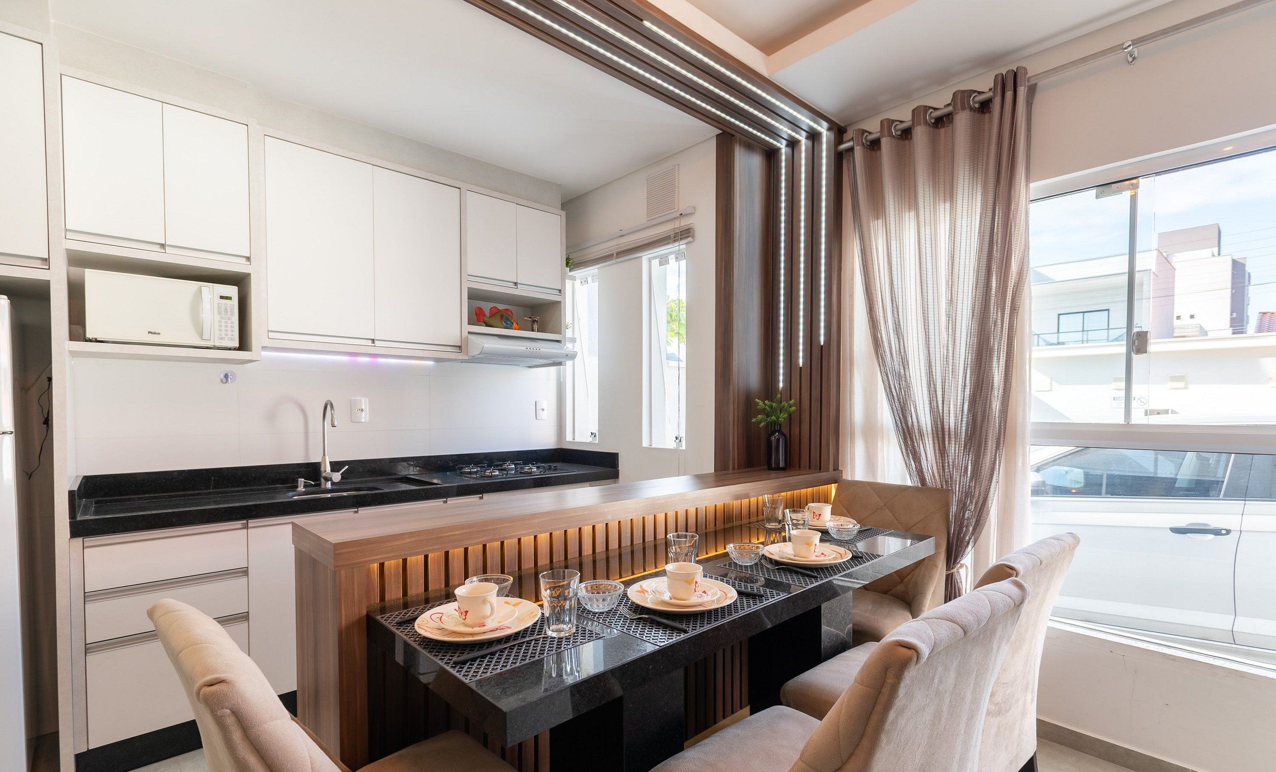 Una cocina moderna con una isla central, electrodomésticos integrados y vistas de la ciudad a través de amplios ventanales.