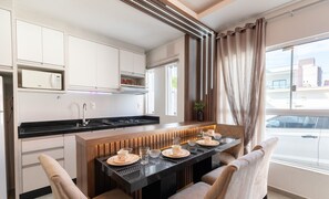 Een moderne keuken met een centraal eiland, ingebouwde apparatuur en een uitzicht op de stad door grote ramen.