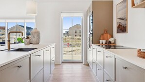 A modern kitchen with a view to the outside, featuring a large window, a sink, and cabinets. - Cozy home in Løkken with WiFi (Løkken)