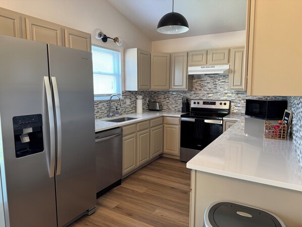 A modern kitchen with stainless steel appliances, a dishwasher, a microwave, and a stove. - 4BR Retreat Great for Groups with Office Space, Fire Pit & Large Fenced Yard (Wichita)