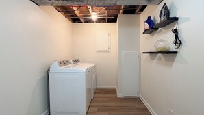 A laundry room with a washing machine and dryer, wooden flooring, and a door.