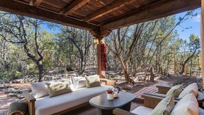 An outdoor seating area with a wooden pergola, cushioned sofas, and a round table. - Authentic Adobe Retreat - Family & Group Getaway (Santa Fe)