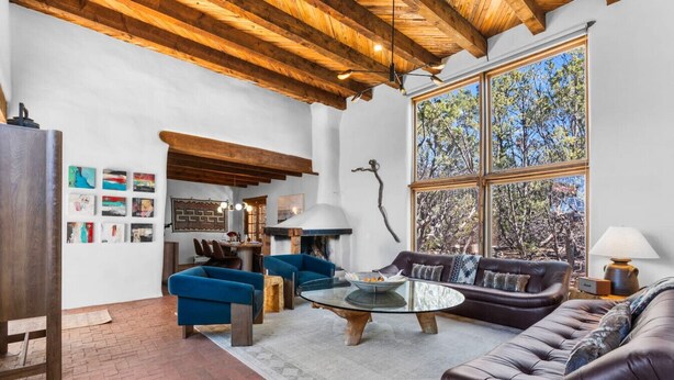 A spacious living area with a fireplace, large windows, and a rustic ceiling. - Authentic Adobe Retreat - Family & Group Getaway (Santa Fe)