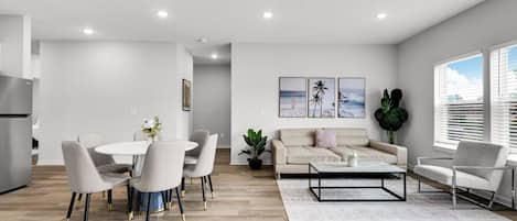 A modern living room with a dining area, a sofa, and a coffee table.