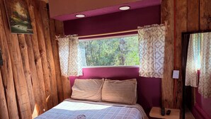 A wooden cabin-style room with a bed, pillows, and a window with curtains. - Cabaña 1 Hogar de leña puente colgante (Mineral del chico)