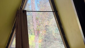 Una habitación pequeña y triangular con una cama, una ventana y una cortina.