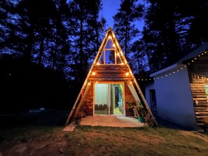A triangular wooden cabin with a glass door and windows, surrounded by trees. - Cabaña 4 Ladera By GEstores (Mineral del chico)