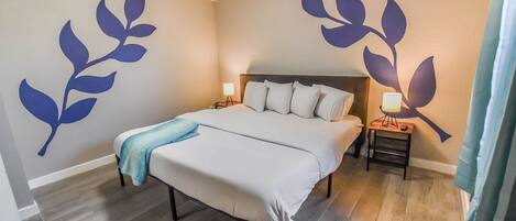 A bedroom with a bed, bedside tables, and wall art.