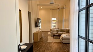 Een moderne woonkamer met een hoekbank, een salontafel en een televisie aan de muur.