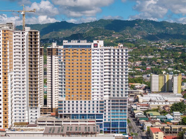 A high-rise building with multiple floors, a construction crane, and a mountainous backdrop.