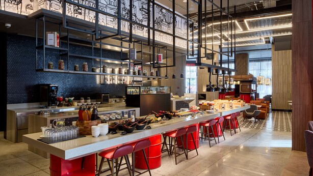 A modern kitchen with a long counter, red stools, and various kitchen appliances. - Radisson RED Cebu Mandaue (Mandaue)