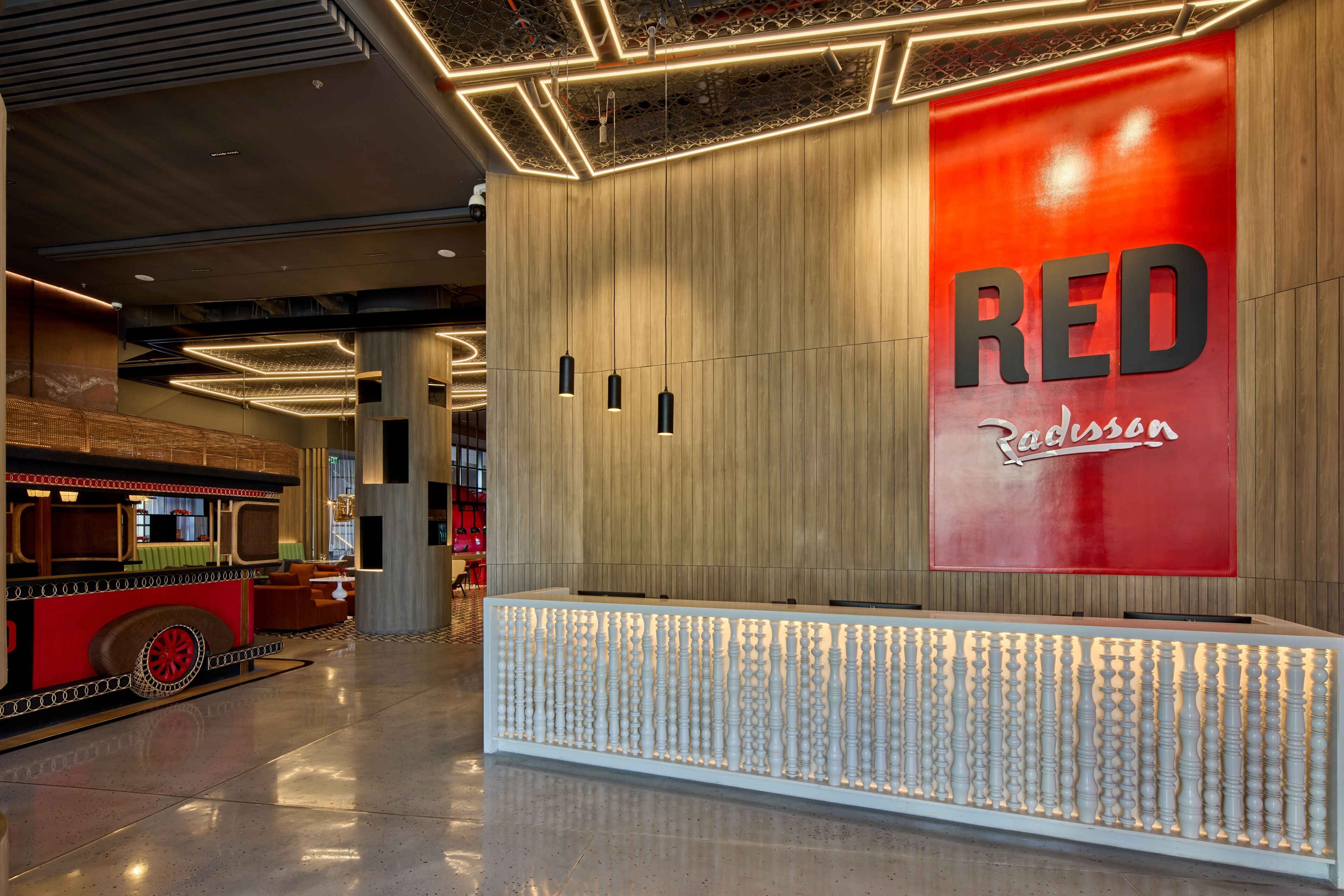 A reception area with a prominent RED sign, a modern design with wooden panels, and a unique seating area resembling a train.