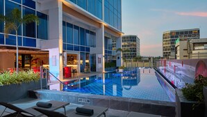 A rooftop pool with lounge chairs, a restaurant, and modern buildings in the background. - Radisson RED Cebu Mandaue (Mandaue)