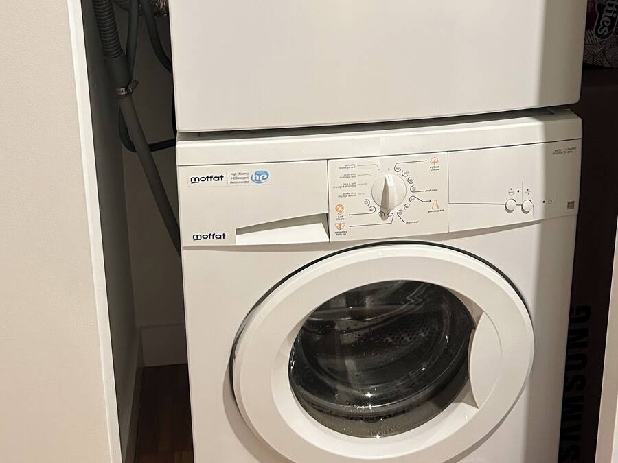 Uma máquina de lavar e secar empilhadas, com painéis de controle e mangueiras.