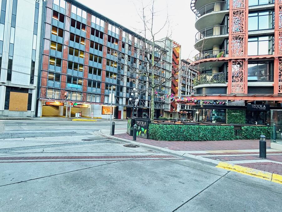 A modern urban street with a mix of commercial and residential buildings, including a restaurant and a bar.