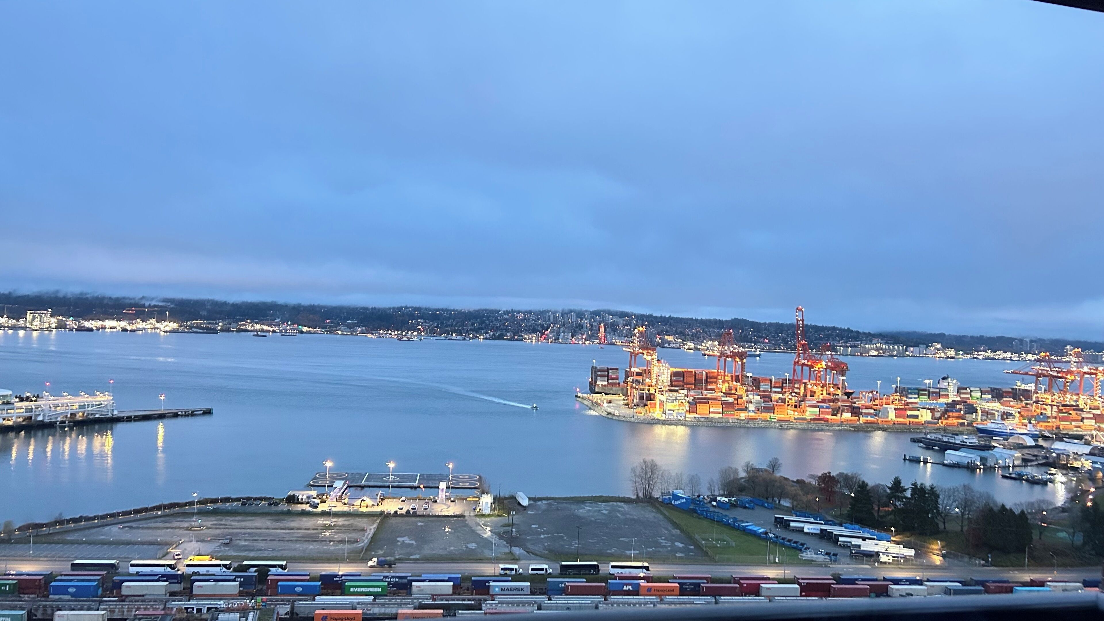 A port with shipping containers, cranes, and a dock.