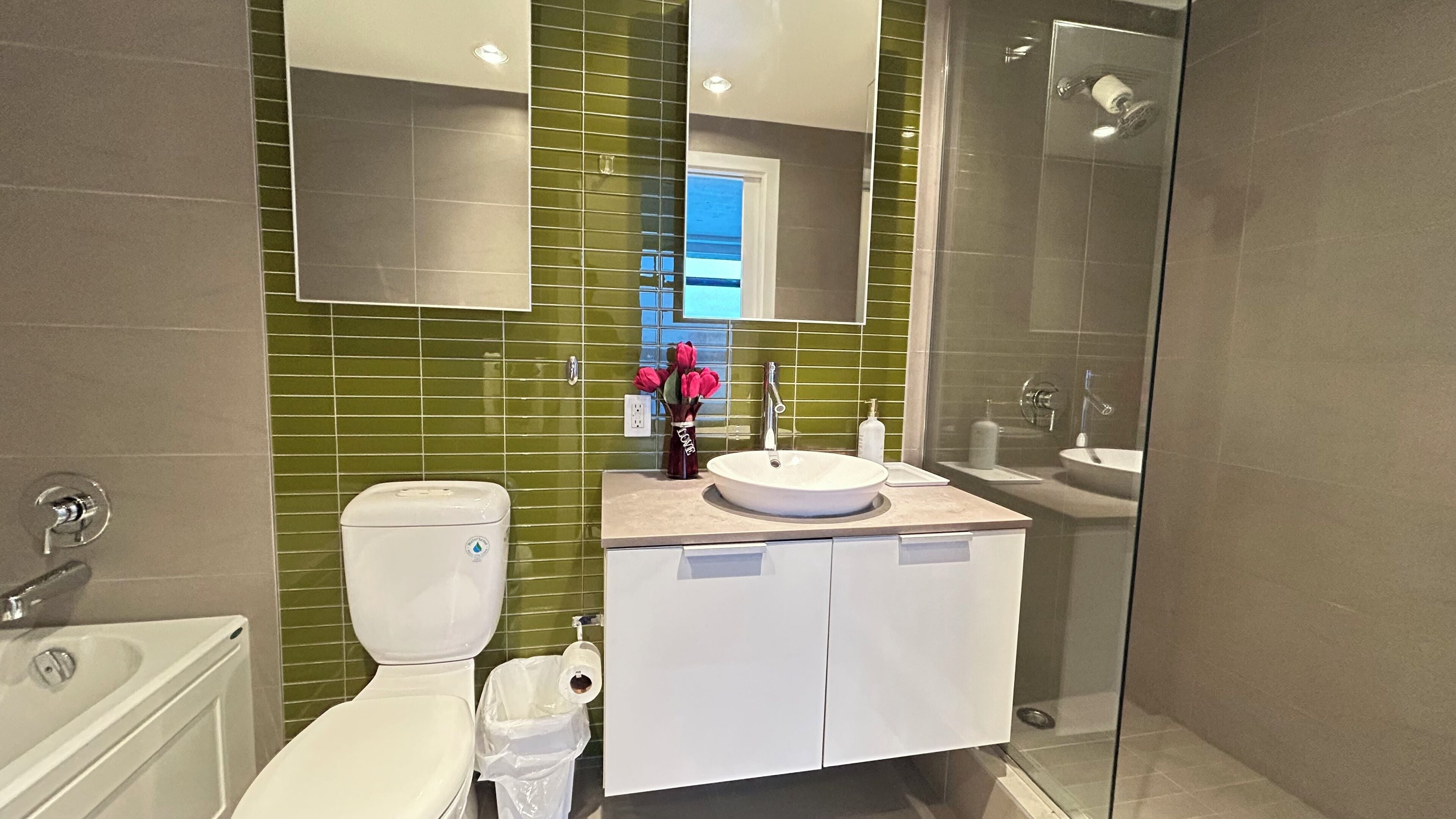 A modern bathroom with a toilet, sink, and shower.
